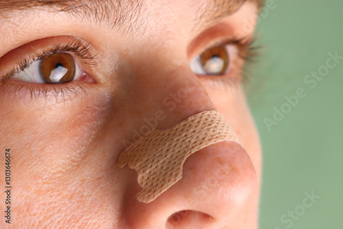 Woman with a nasal strip in the nose apply. Close view of a nasal strip in the nose