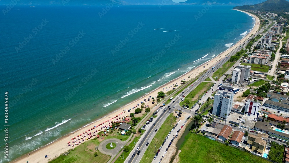 Fototapeta premium Linda vista aerea com drone sobre o mar com montanhas e cidade ao fundo com cores vibrantes.