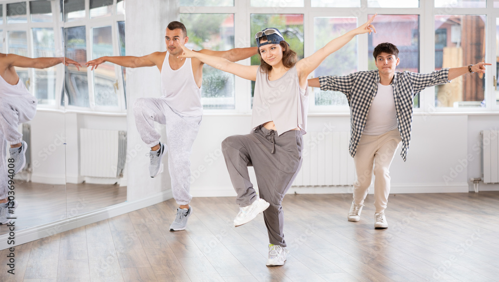Naklejka premium Active young men and girls practicing hip-hop dance in training hall during group dancing classes