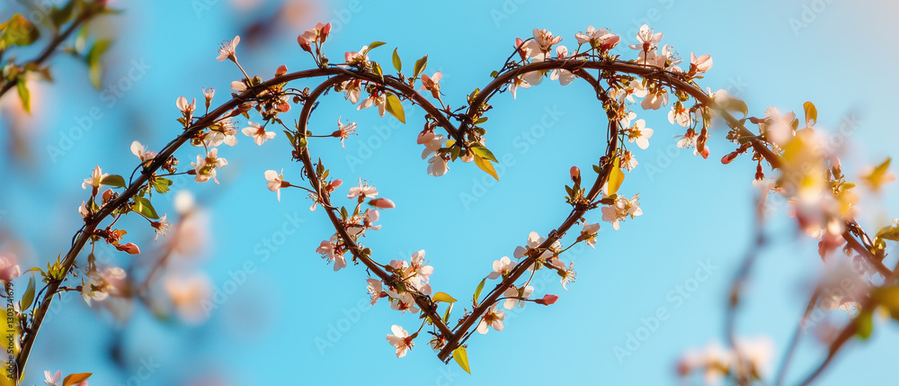 A heart formed by intertwining vines, bursting with tiny spring blossoms, against a sky-blue background A heart formed by intertwining vines, bursting with tiny spring blossoms, against a sky-blue background