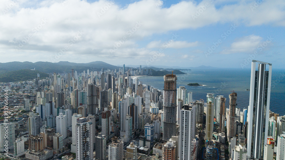 Fototapeta premium Drone perspective of Balneário Camboriú, showing the vibrant city with tall, modern skyscrapers along the coast and the endless Atlantic Ocean in the distance.