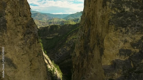 Drone footage of Karadakh Gorge, Dagestan, navigating closely between two towering mountains covered in alpine forests.