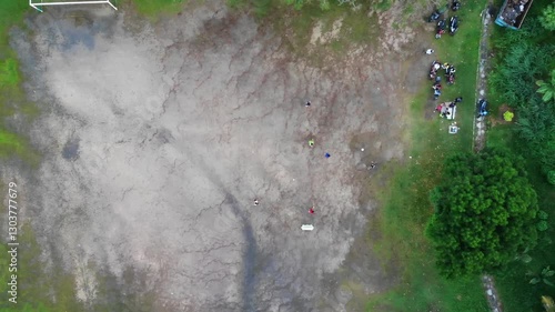 Aerial top down drone shot of people playing football on a field