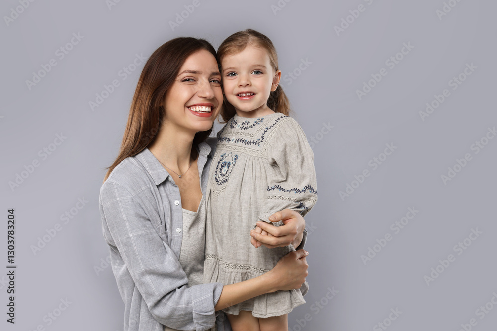 Portrait of happy mother with her cute little daughter on grey background Portrait of happy mother with her cute little daughter on grey background