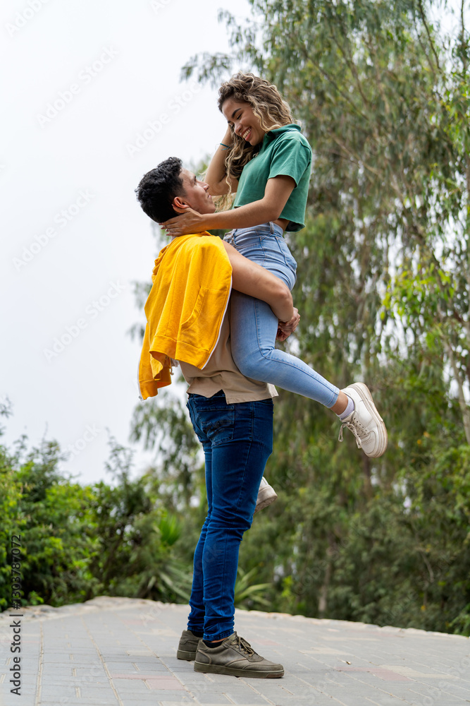Fototapeta premium Boyfriend lifting his girlfriend while strolling in a park