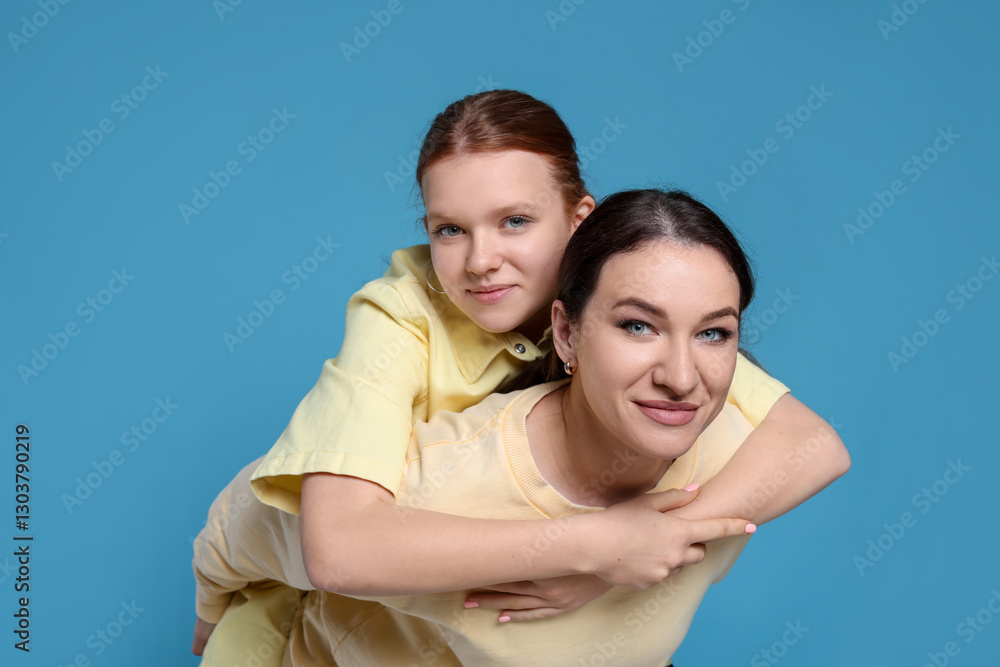Portrait of beautiful mother with teenage daughter on light blue background Portrait of beautiful mother with teenage daughter on light blue background