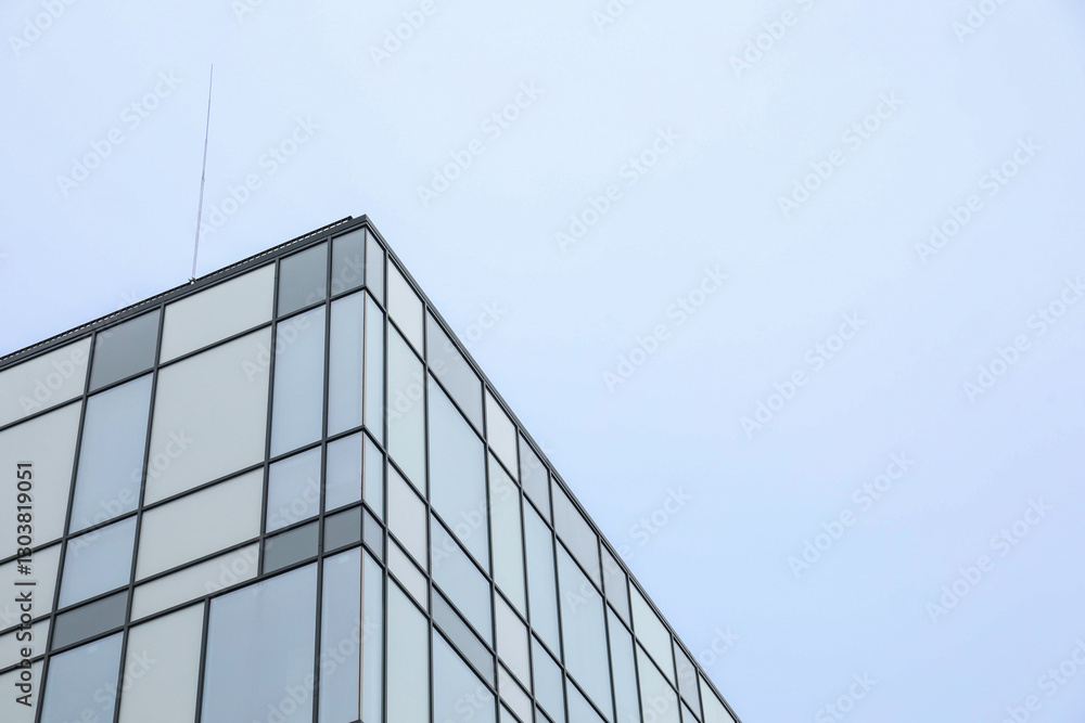 Modern building with many windows against blue sky, low angle view. Space for text Modern building with many windows against blue sky, low angle view. Space for text