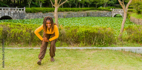 Young black woman performing leg stretches in local park.