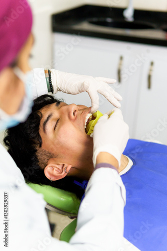 Canvas Print Dentist placing cheek retractor in patient's mouth during dental checkup