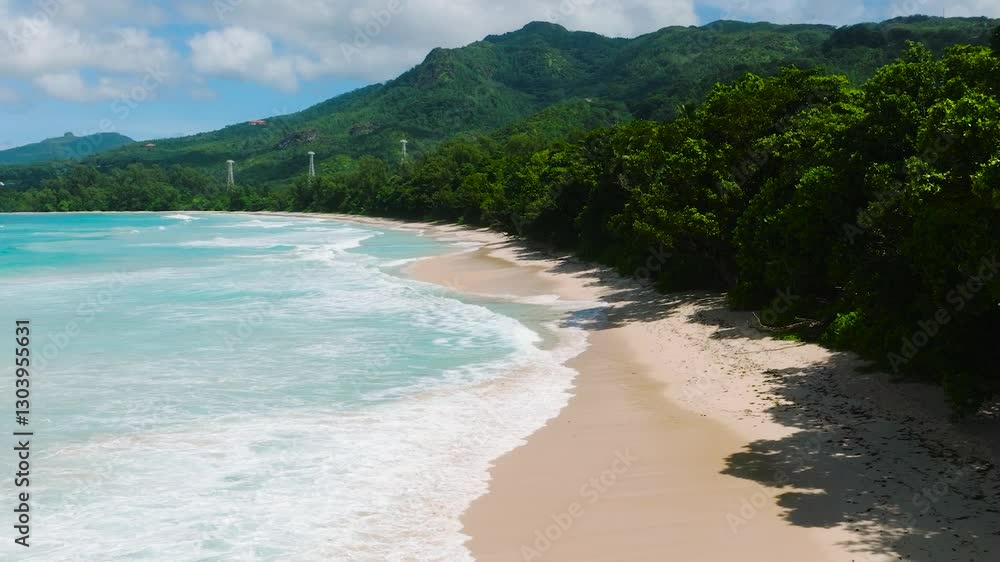 Sandy beach with dense green forest and calm turquoise waves under a partly cloudy sky. Seychelles, Mahe. Sandy beach with dense green forest and calm turquoise waves under a partly cloudy sky. Seychelles, Mahe.