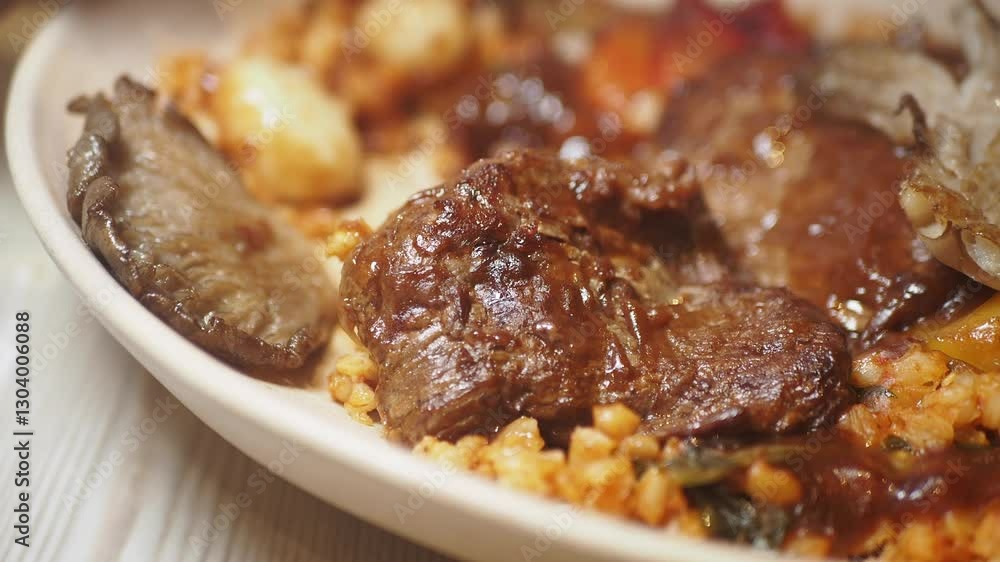 Savory meat dish with grains and vegetables on a white plate Savory meat dish with grains and vegetables on a white plate