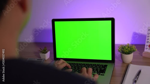 Laptop with a green screen: A person types at the laptop with a green screen, showcasing a modern workspace.
