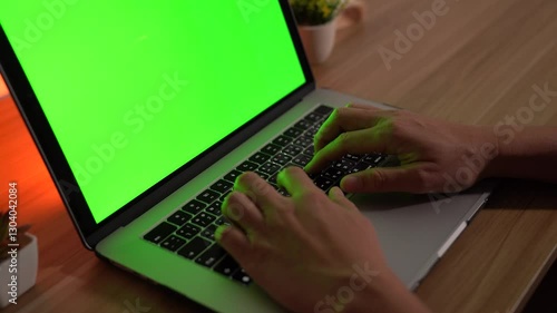 Digital Workflow: Person typing on a laptop with a green screen, with a modern desk and a soft glow, highlighting productivity and technology.