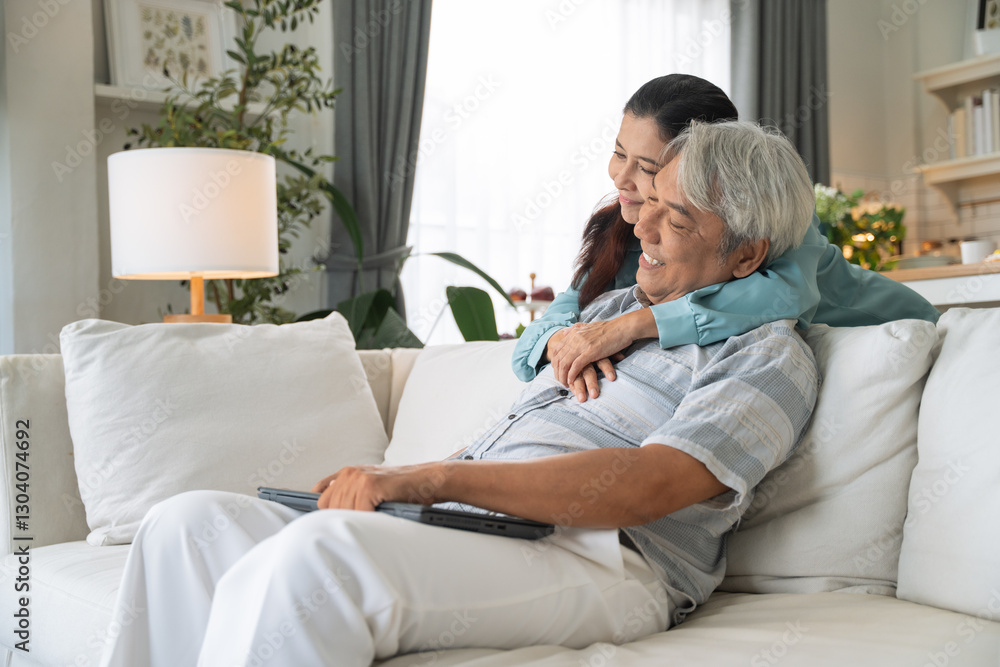 Asian senior woman embracing husband on couch afther finish working with laptop. Family love and support concept. Couple spending time together at home Asian senior woman embracing husband on couch afther finish working with laptop. Family love and support concept. Couple spending time together at home