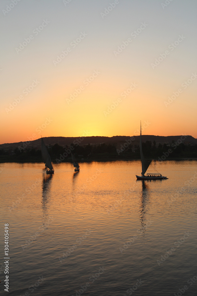 Felucca sailing on Nile River during sunset at Aswan, Egypt Felucca sailing on Nile River during sunset at Aswan, Egypt