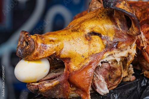 Chancho hornado, traditional Ecuadorian roasted pork with crispy golden skin, served with a boiled egg, displayed at a local market food stall.