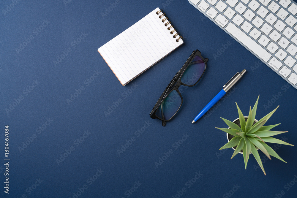 Workspace with keyboard, laptop, office supplies, pen, green leaf. Flat lay, top view blue office desk Workspace with keyboard, laptop, office supplies, pen, green leaf. Flat lay, top view blue office desk