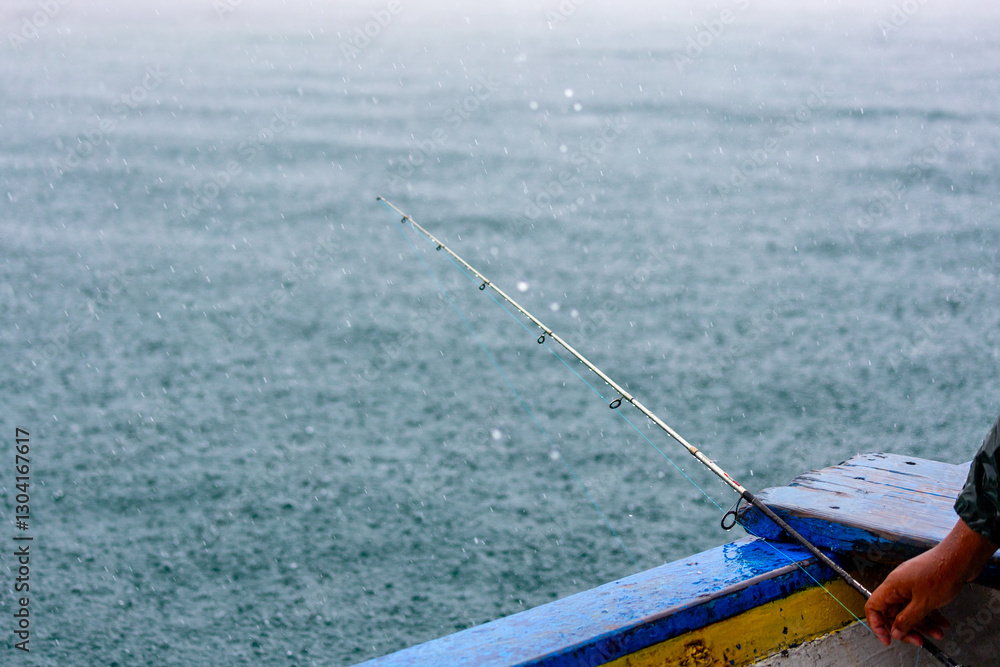 Obraz premium Fishing rod in the boat under the rain. Fishing rod, sea, boat and rain.