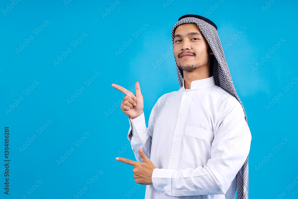 Elegant Young Arab Male Pointing Aside To Ads Space Isolated On Blue Studio Wall Elegant Young Arab Male Pointing Aside To Ads Space Isolated On Blue Studio Wall