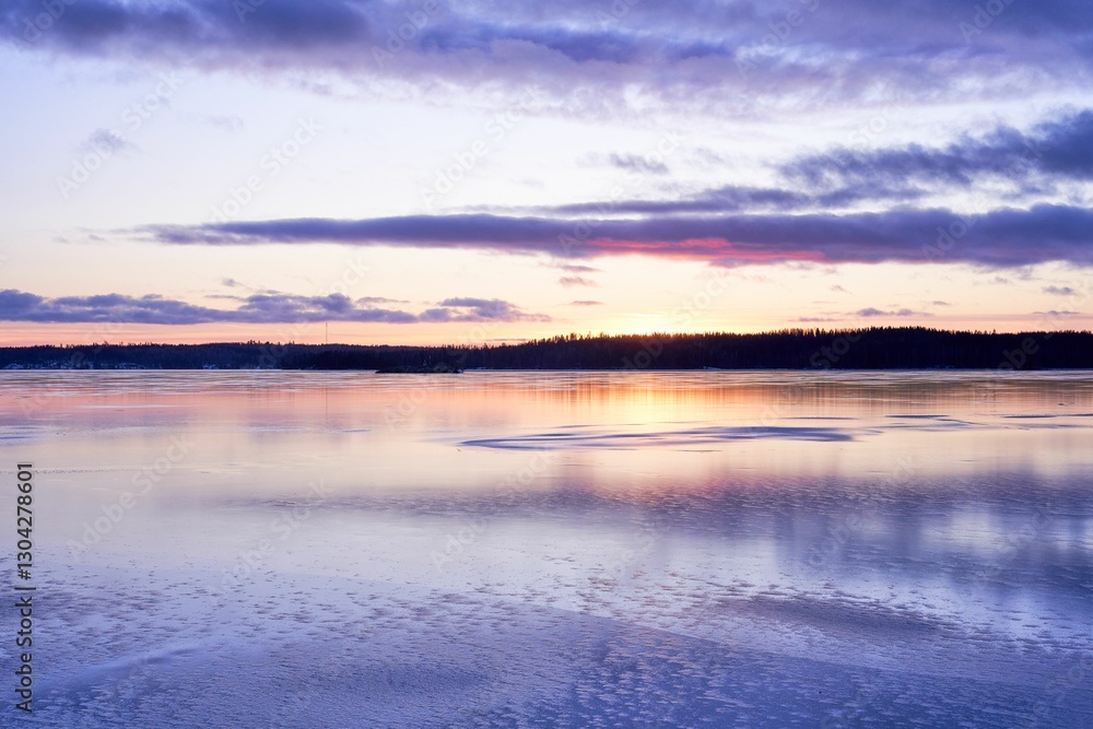 Fototapeta premium Serene winter sunset over a frozen lake.