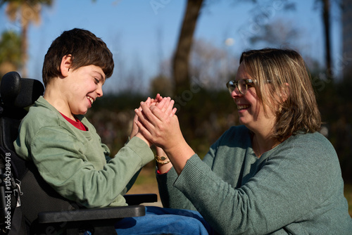 Happy child with disability playing with his educator outdoors - cerebral palsy concept