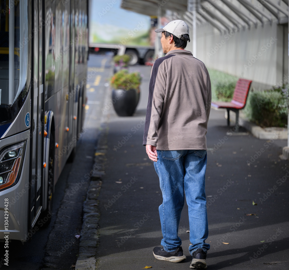 Man walking to board the bus at bus stop. Auckland.