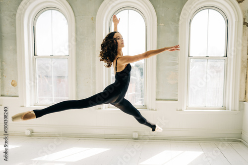 Ballet dancer mid-leap, displaying graceful form in a vintage studio