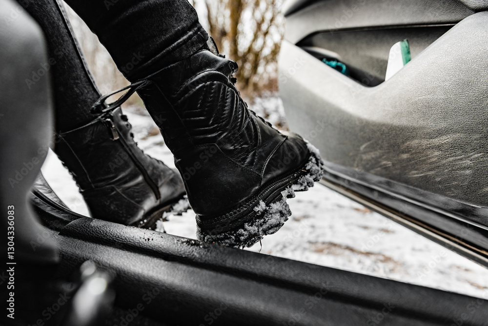 Woman's legs in winter boots with snow boarding a car.