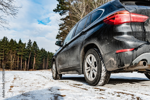 Obraz na płótnie Very dirty salty black car is parked on nature covered by snow in winter. w salonie