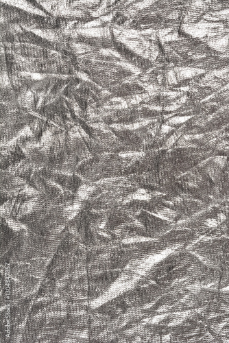 A close-up shot of crumpled silver fabric, showcasing its reflective surface and intricate texture