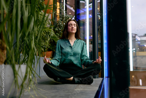 Woman practicing mindfulness meditation in a modern office lobby photo