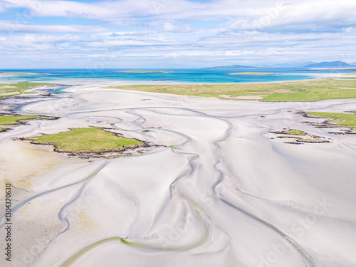 Aerial view of Clachan Sands in North Uist, Scotland, showcasing exposed sand patterns at low tide with turquoise water and white sands under summer sunshine. photo