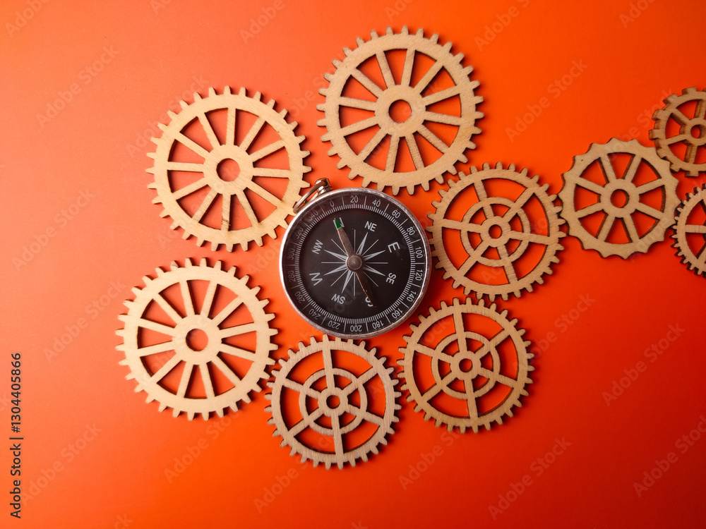 Closeup compass with wooden gear on a orange background Closeup compass with wooden gear on a orange background