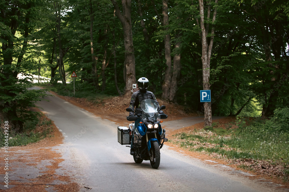 Motorcycle rider on the road in the forest Motorcycle rider on the road in the forest