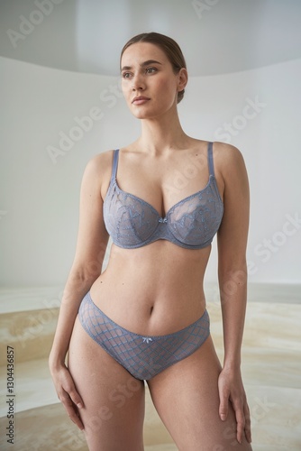 Sensual woman in lace blue bra posing in soft lighting, boudoir style