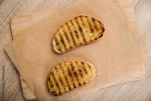 Toasted ciabatta slices for bruschetta lie on paper on the table