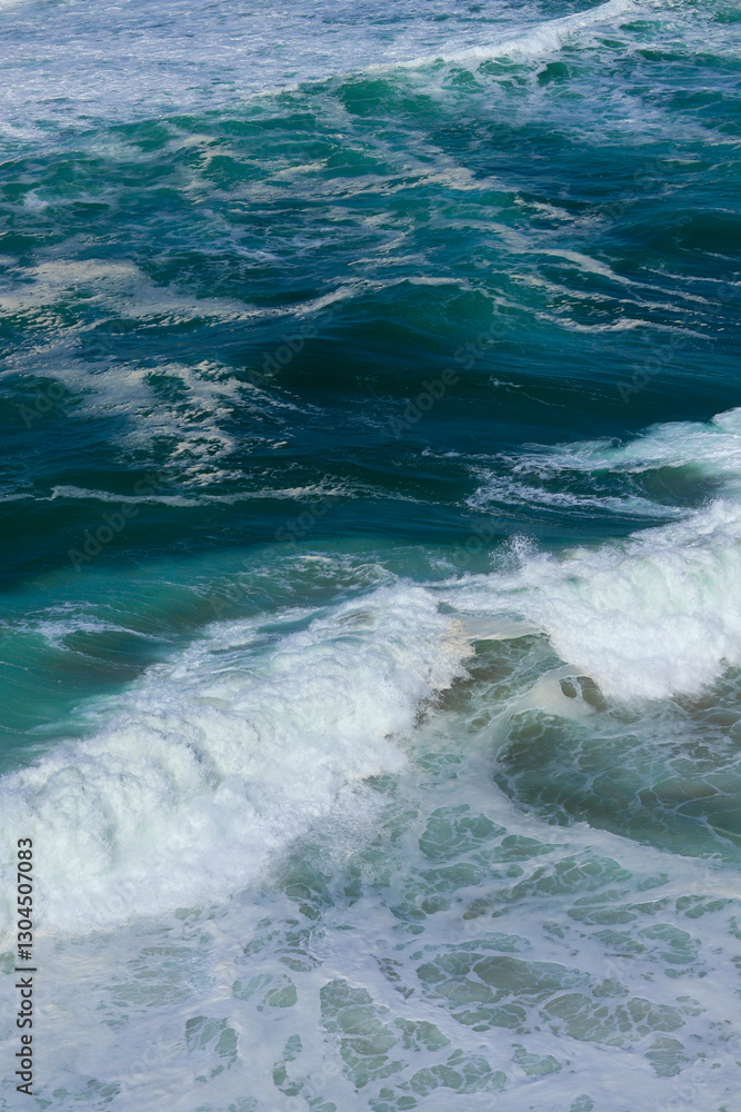 Fototapeta premium Ocean waves in Portugal. Blue and green water with white foam moving in the Atlantic Ocean. The power and beauty of nature in motion.