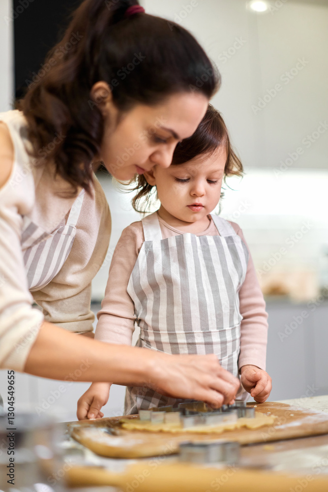 Happy family mother and little child daughter cutting cookies of raw gingerbread dough in kitchen Happy family mother and little child daughter cutting cookies of raw gingerbread dough in kitchen