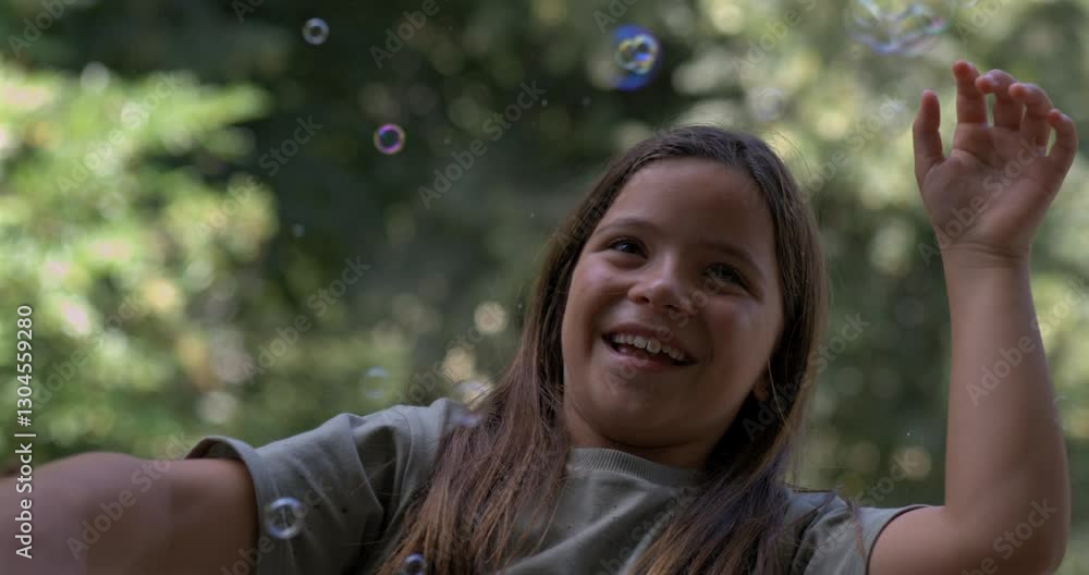 Girl laughing and smiling while bubbles float around her in slow-motion at 800 fps, enjoying a whimsical and playful moment outdoors with a natural green background Girl laughing and smiling while bubbles float around her in slow-motion at 800 fps, enjoying a whimsical and playful moment outdoors with a natural green background