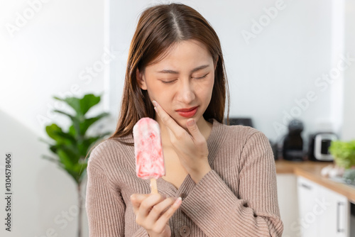 Tableau sur toile Asian Woman touching her chin feeling sensitive teeth when eating an ice cream