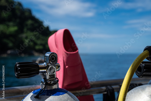Diving equipment on a liveaboard. Airtank and pink fins in front of an island