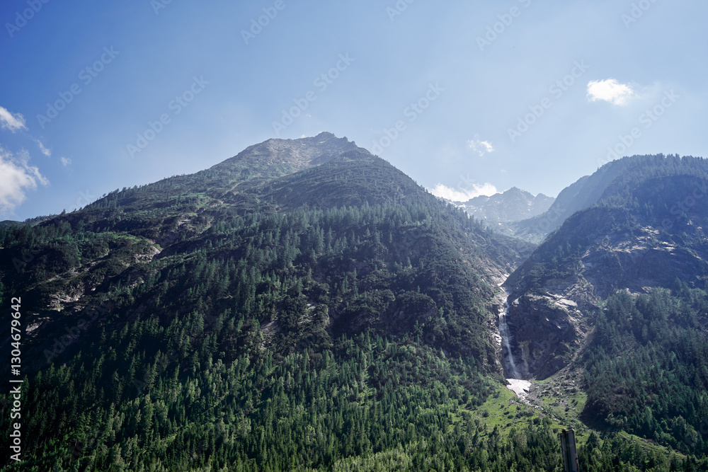 Naklejka premium Majestic Mountain Landscape with Forested Peaks and Clear Blue Sky..