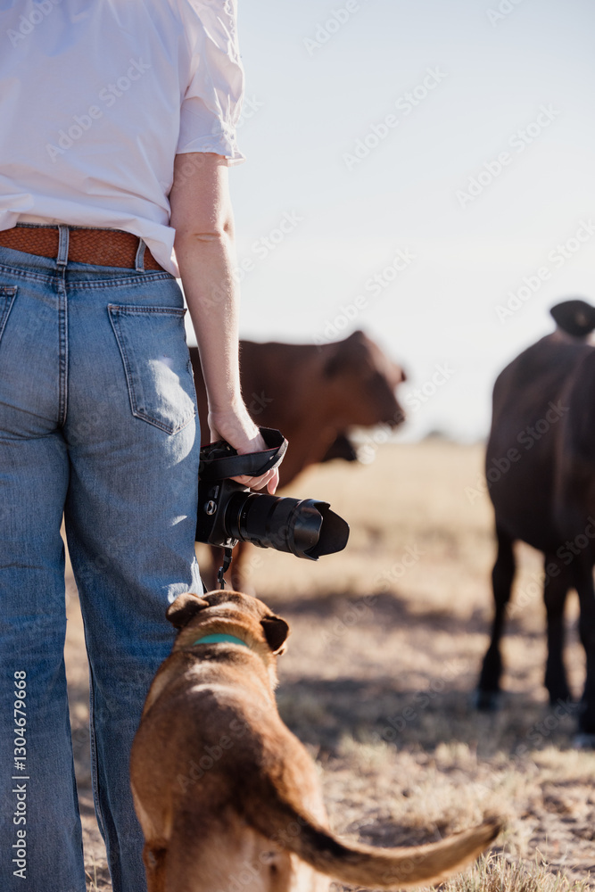 Woman standing beside pet dog holding camera. Woman standing beside pet dog holding camera.