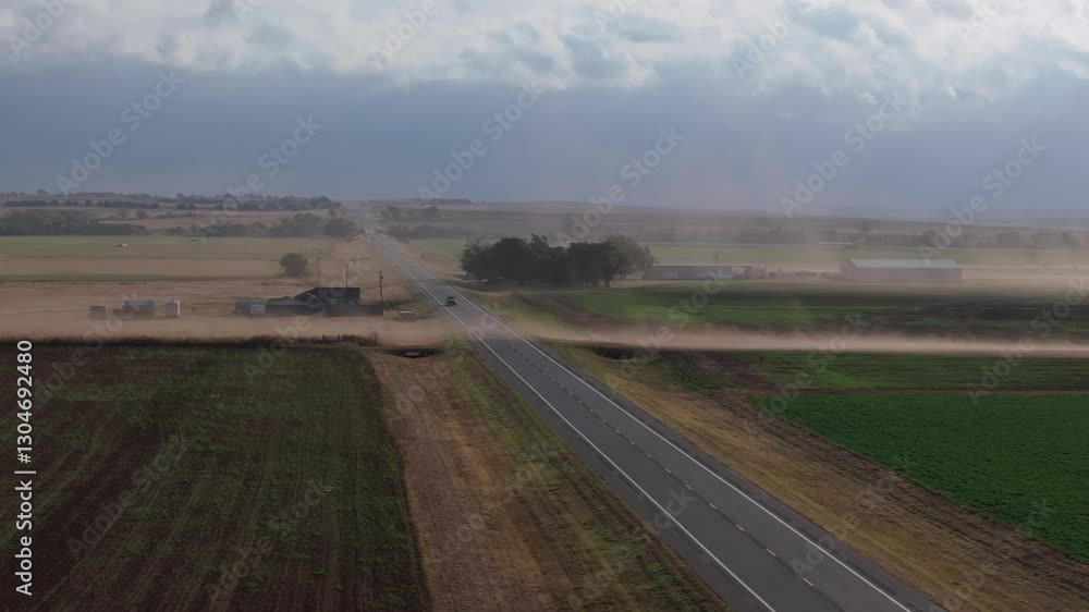 Dust swirling along an empty Oklahoma highway, showing rural landscape and wind Dust swirling along an empty Oklahoma highway, showing rural landscape and wind