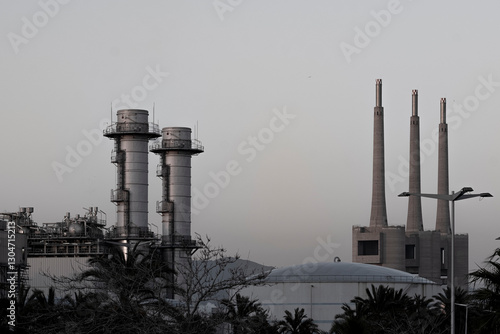 Distant view of an industrial complex with multiple smokestacks, highlighting urban manufacturing and energy sectors.