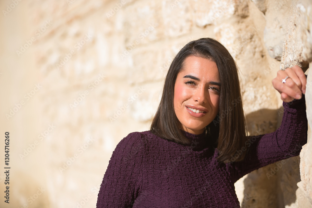Portrait of young, beautiful, brunette, Hispanic woman, wearing a purple dress, leaning against a wall, looking at the camera smiling, happy and triumphant. Concept beauty, fashion, trendy. Portrait of young, beautiful, brunette, Hispanic woman, wearing a purple dress, leaning against a wall, looking at the camera smiling, happy and triumphant. Concept beauty, fashion, trendy.