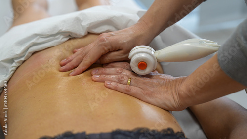 Physiotherapist performs shoulder massage with TECAR therapy on a woman for pain relief