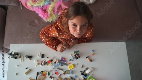Child joyfully arranging colorful building blocks on table in cheerful living room