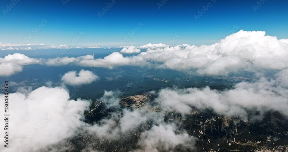 Aerial drone shot of mountainous landscape covered by dense layer of white clouds. Blue sky contrasts with misty formations, creating surreal breathtaking high-altitude view. Aerial drone shot of mountainous landscape covered by dense layer of white clouds. Blue sky contrasts with misty formations, creating surreal breathtaking high-altitude view.