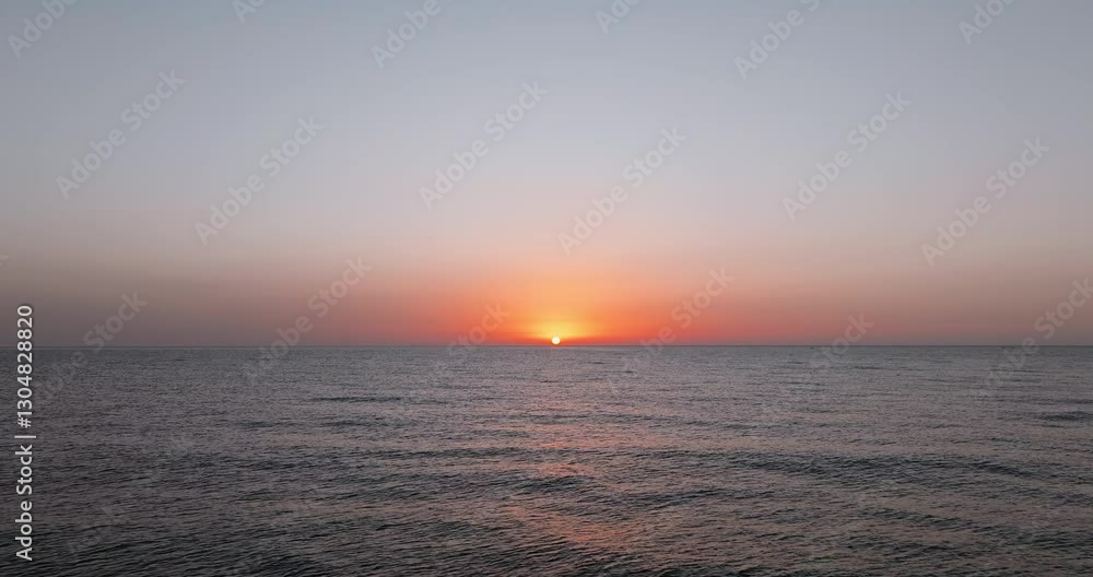 Sunrise over ocean with deep orange sky golden sun casting shimmering reflections on water. Lone bird glides through air, enhancing tranquil scenic beauty early morning summer Sunrise over ocean with deep orange sky golden sun casting shimmering reflections on water. Lone bird glides through air, enhancing tranquil scenic beauty early morning summer